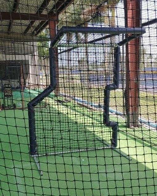 A baseball field with a net and a batting cage.