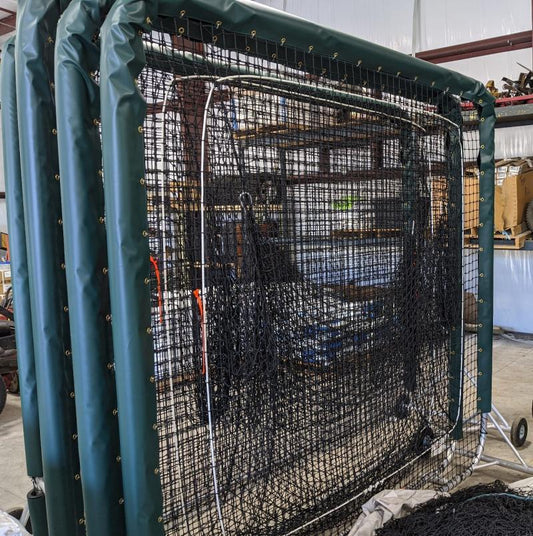 A large cage in the middle of an indoor field.
