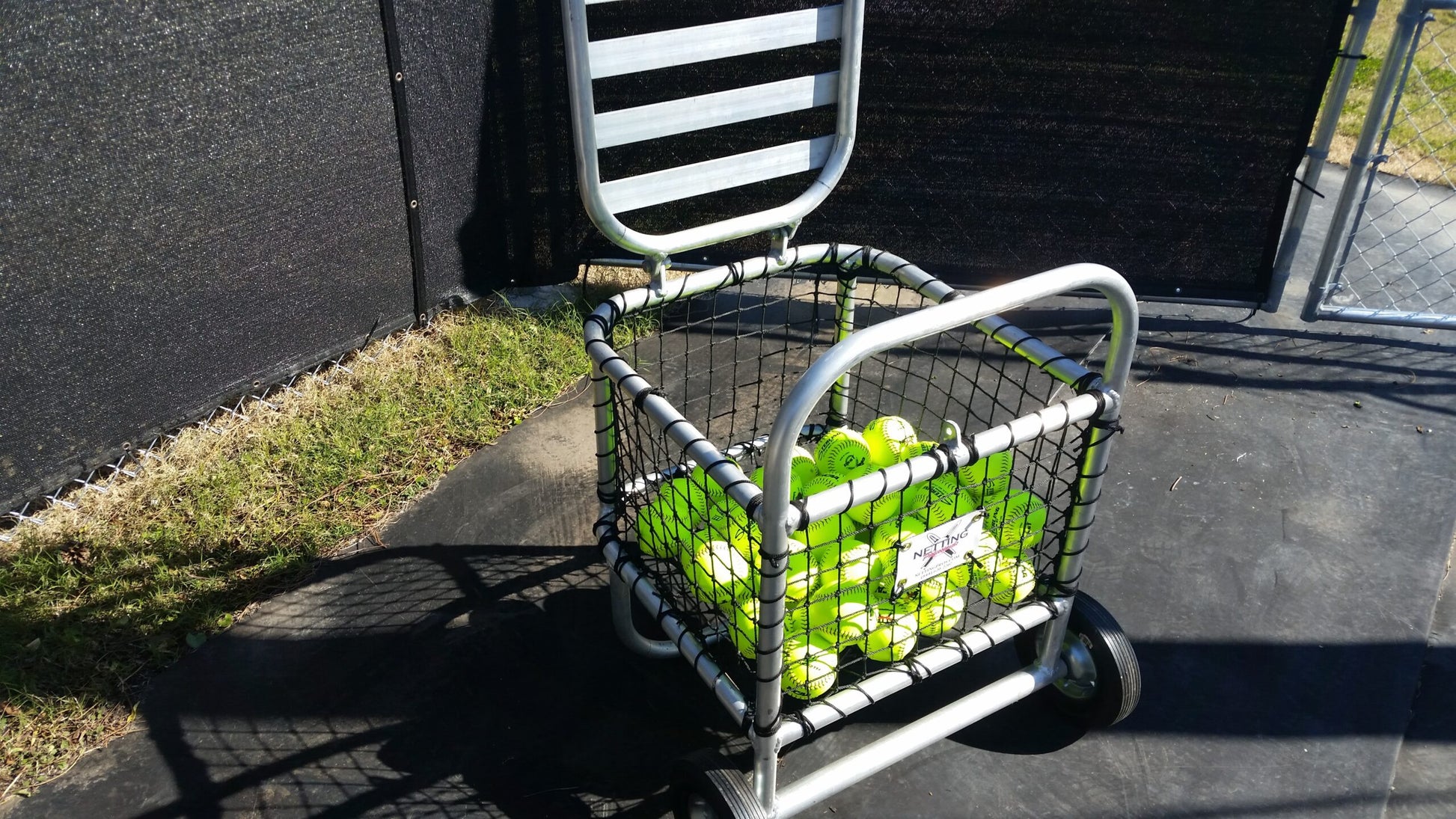 A cart full of tennis balls on the ground.