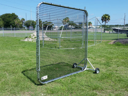 A baseball screen on wheels in the grass.