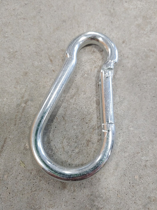 A metal carabiner is laying on the ground.