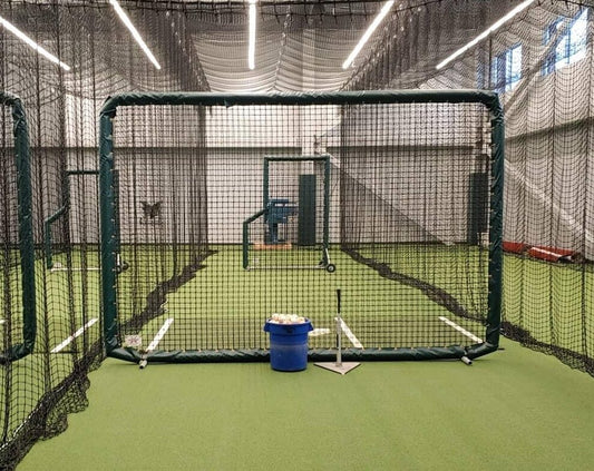 A batting cage with a blue bucket in the middle of it.