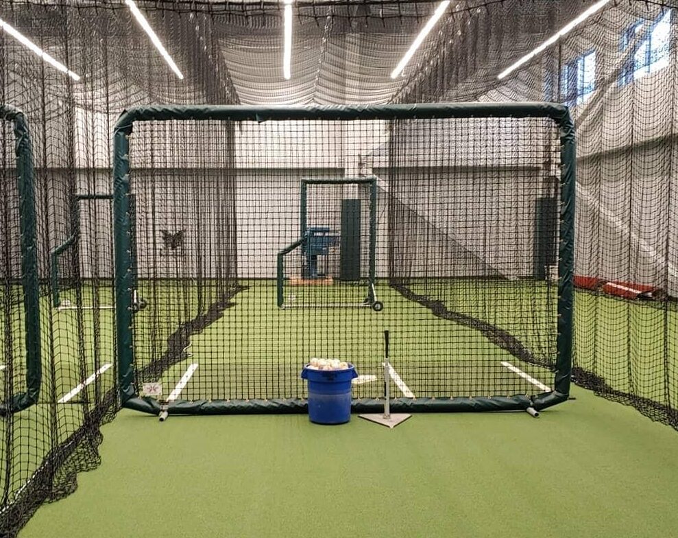 A batting cage with a blue bucket in the middle of it.