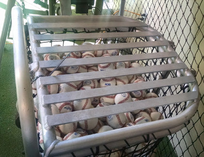 A cage full of baseballs sitting on top of the ground.
