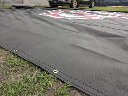 A black tarp covering the ground with a truck in the background.