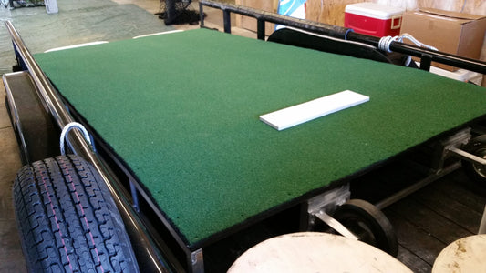 A table with green carpet and white plate on top.