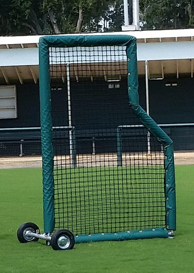 A baseball field with a green cart and black net.