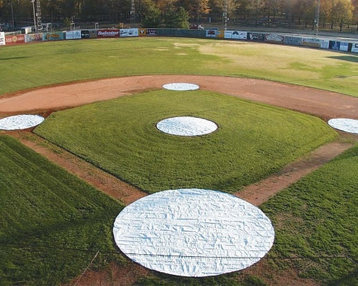 A baseball field with the base and tarp covering it.