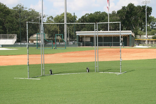 A baseball field with fenced in batting cages.