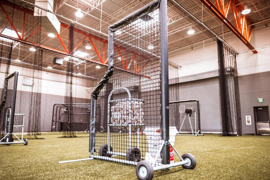 A baseball cage with wheels and poles in it.