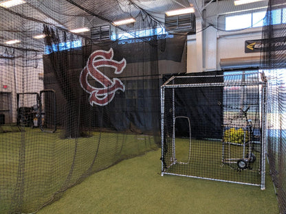 A baseball field with batting cages and a cage.