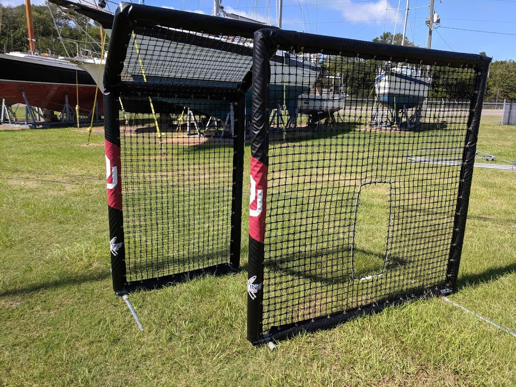 A baseball field with a batting cage in the middle of it.