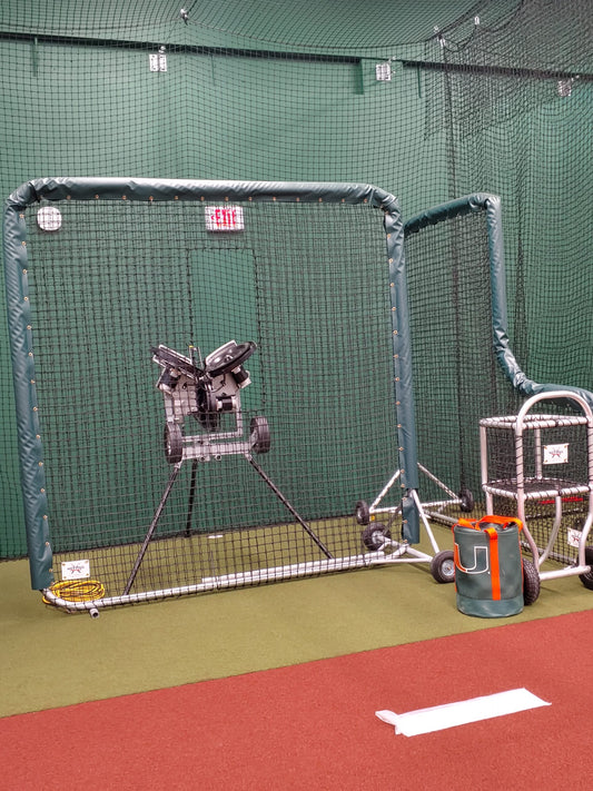 A baseball cage with a catcher 's mitt and ball.
