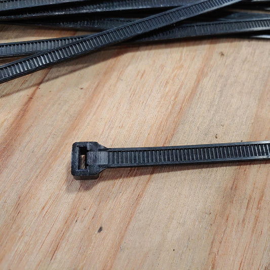 A black cable tie on top of a wooden table.