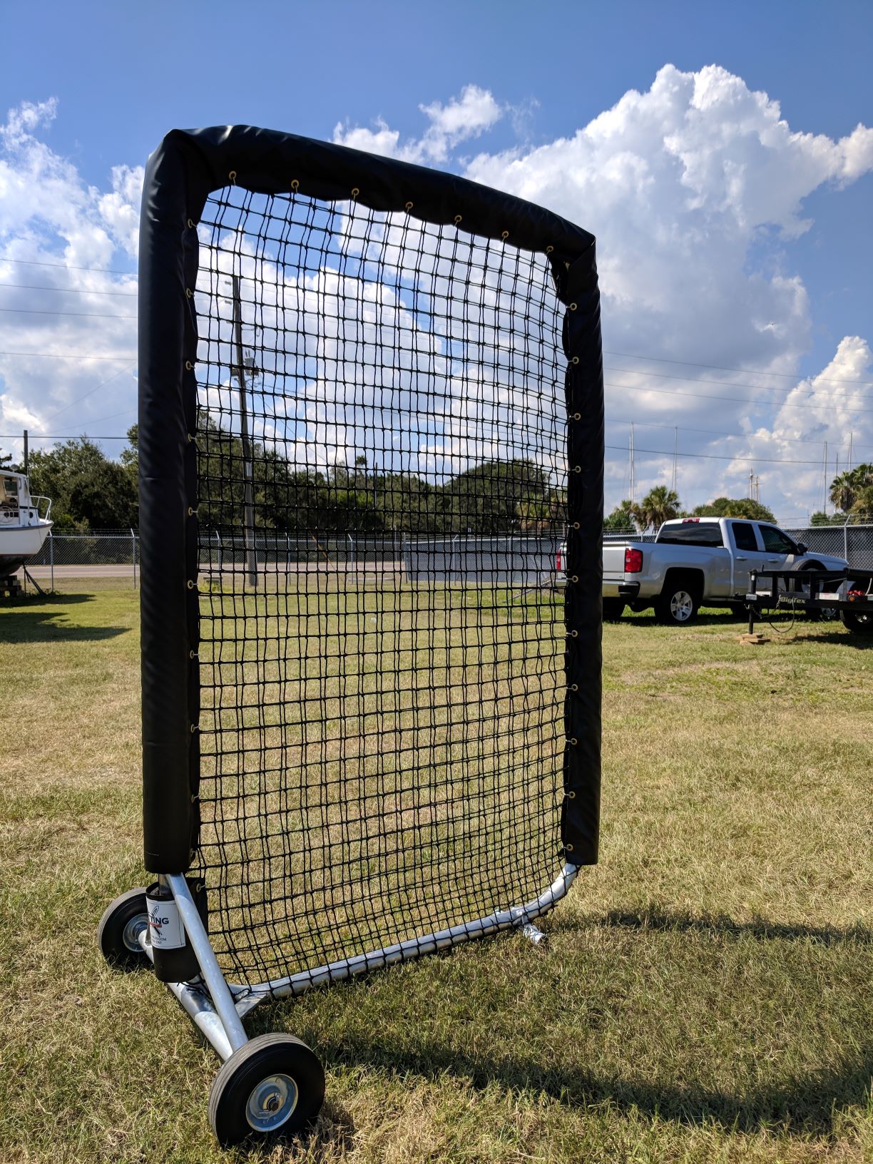A baseball catcher 's screen in the middle of a field.