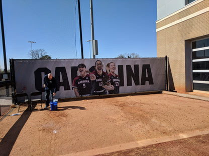 A person is painting the name of a large poster.