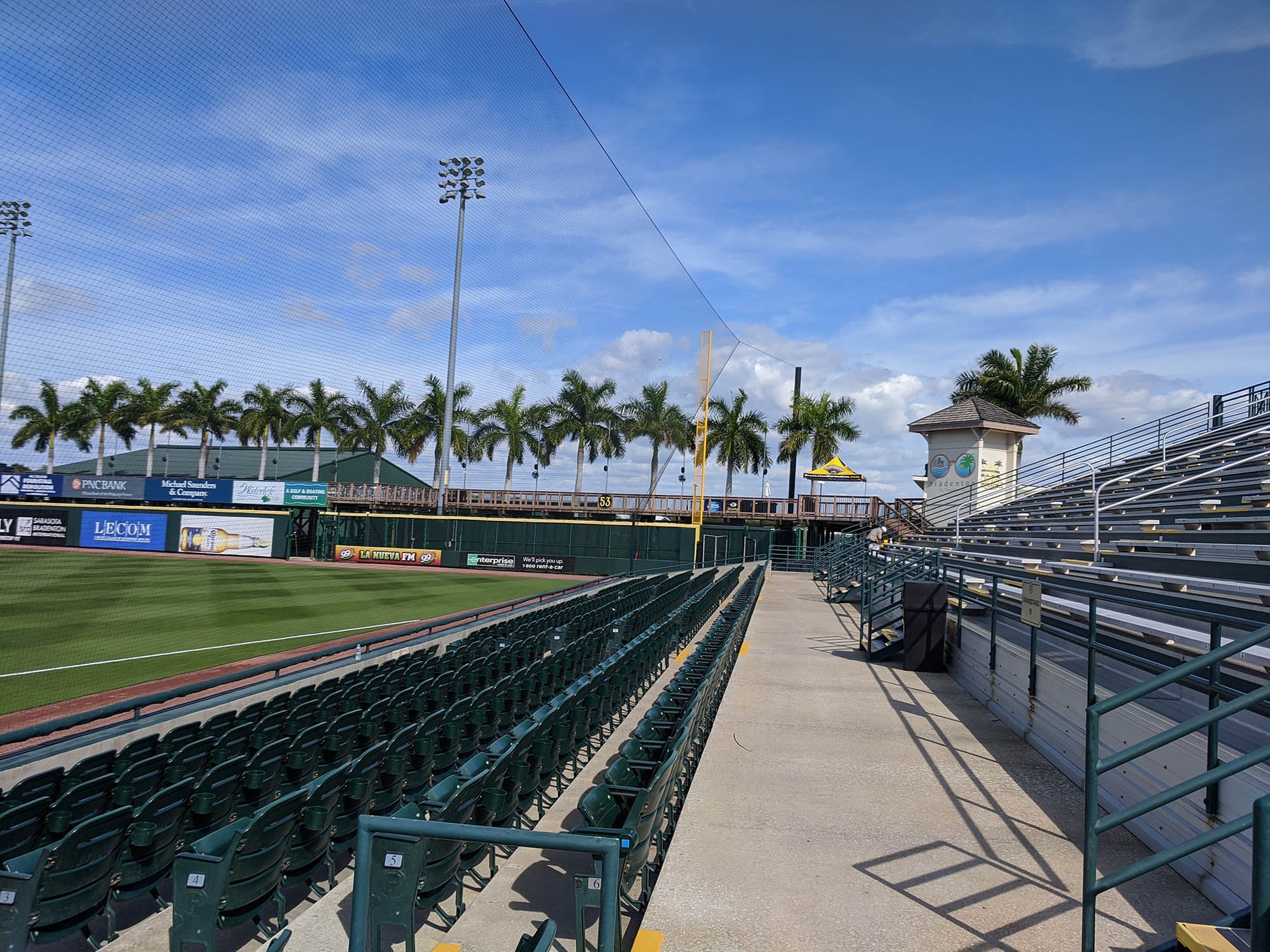 A baseball field with many green seats and palm trees.