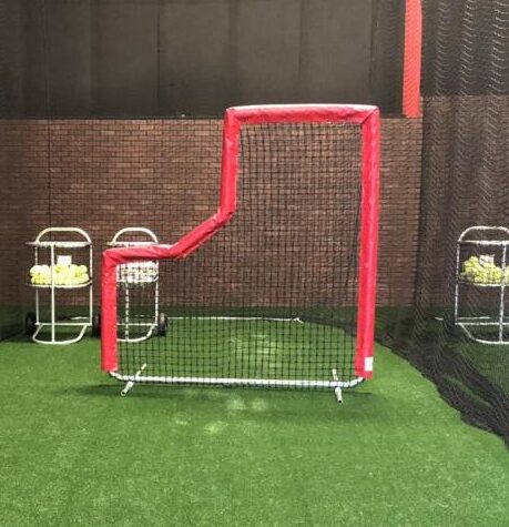 A red net on the grass in front of a wall.