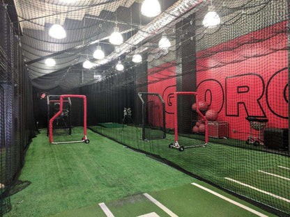 A baseball field with a batting cage and lights.