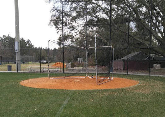 A baseball field with a batting cage and a ball feeder.